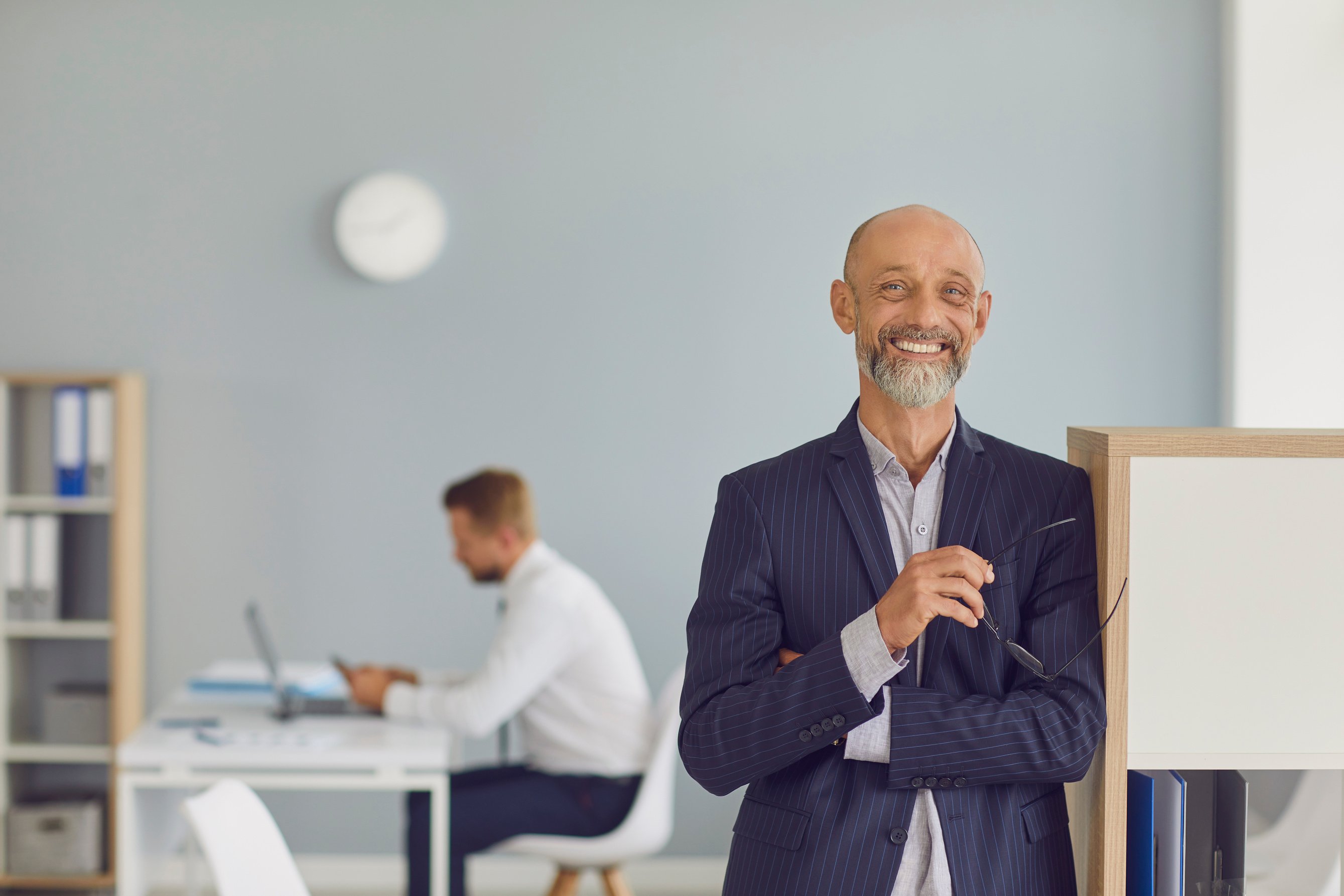 Positive Elderly Chief Company Executive Standing in Office Looking at Camera and Smiling